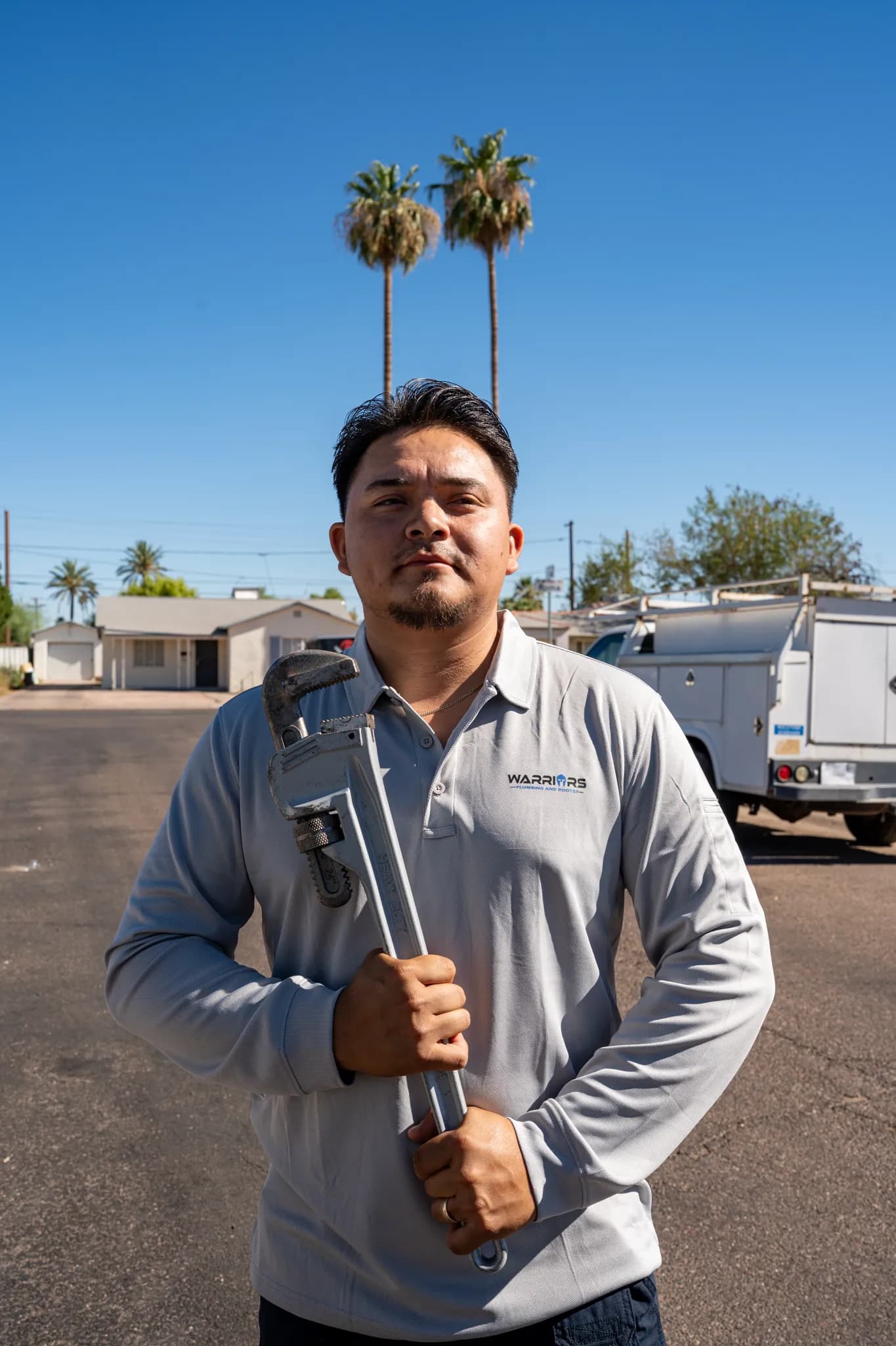 Warriors Plumbing & Rooter technician holding a pipe wrench on a Phoenix street